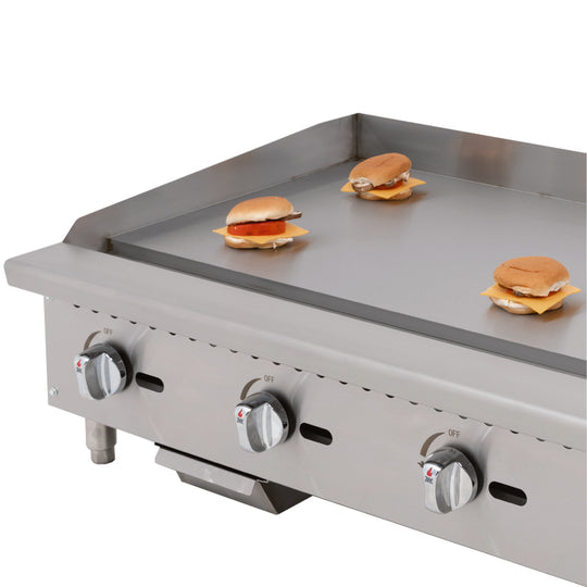 Migali Industries C-G36T 36 Inch Gas Countertop Griddle - griddle plate in use cooking burger patties, showing cooking surface and three control knobs